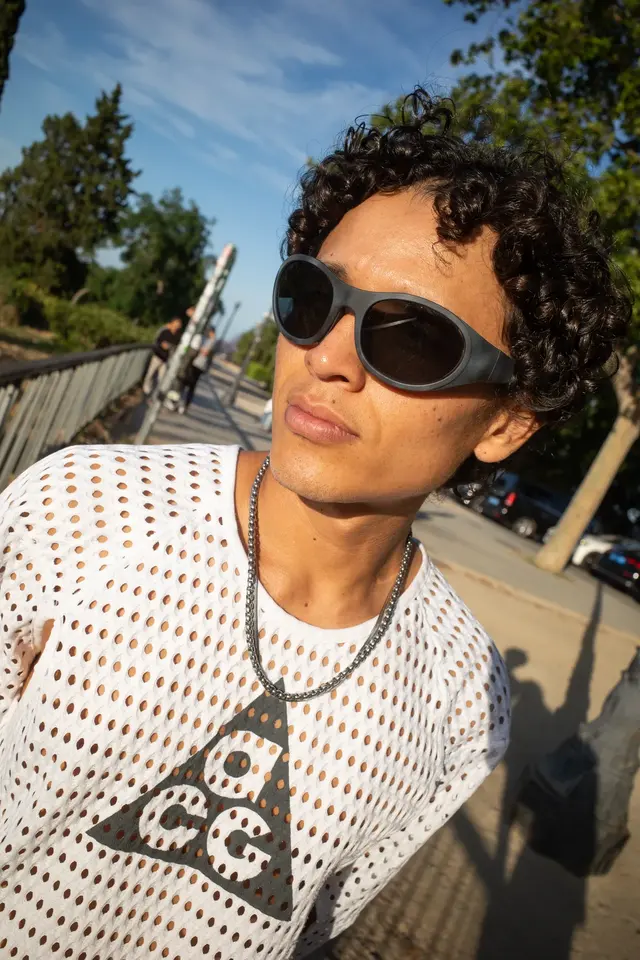 A person in sunglasses and a white knit shirt